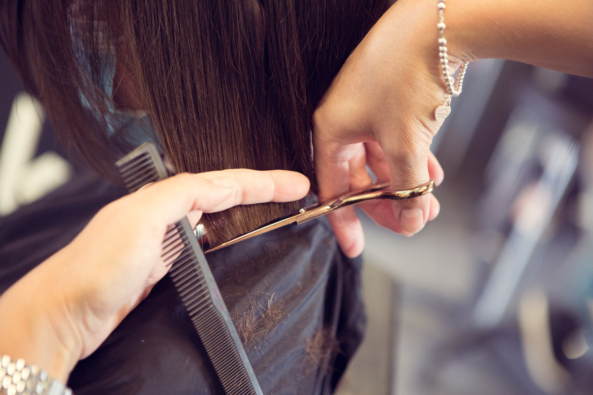Eine Frau lässt sich von einem Friseur die Haare schneiden.