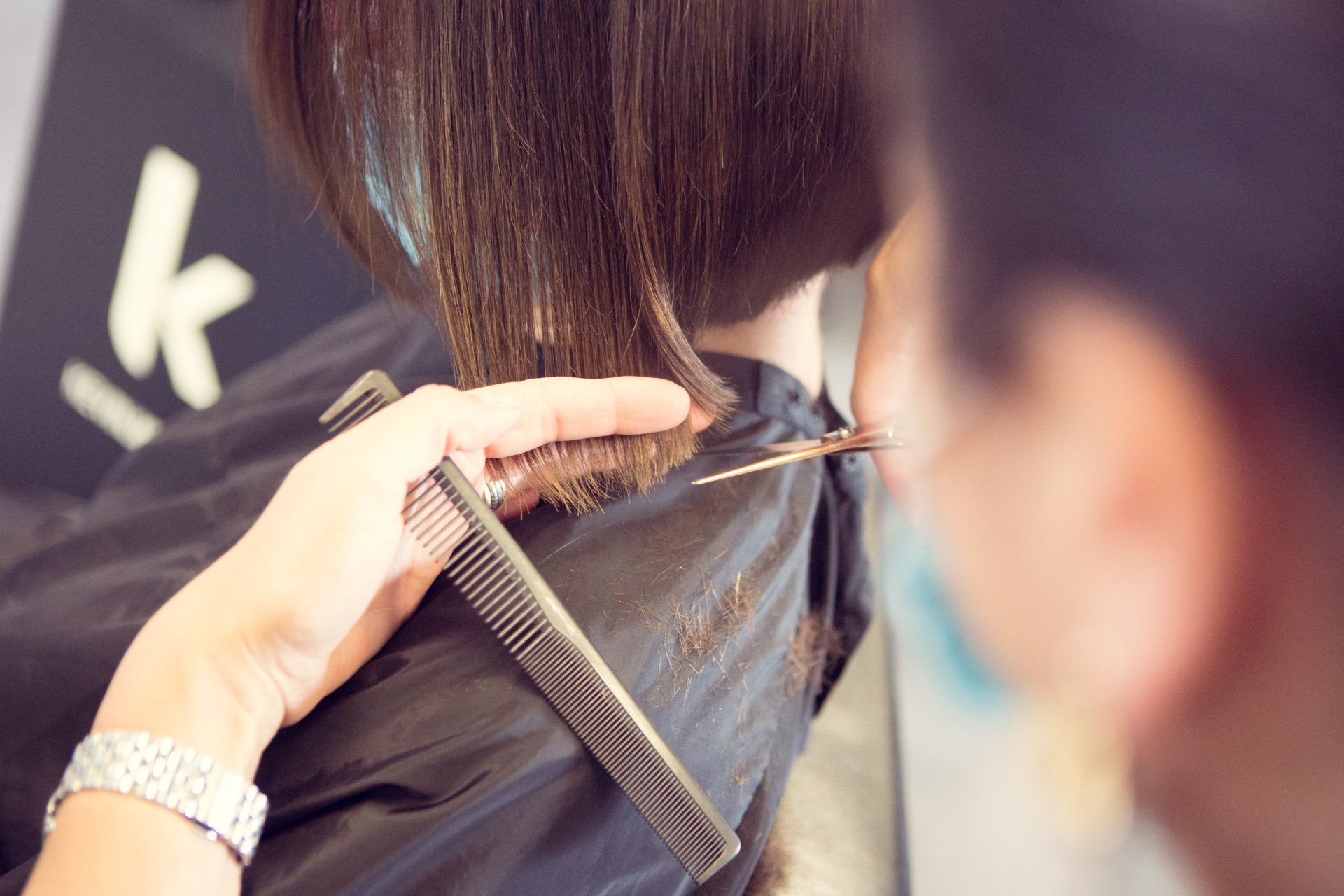 Eine Frau lässt sich von einem Friseur die Haare schneiden.