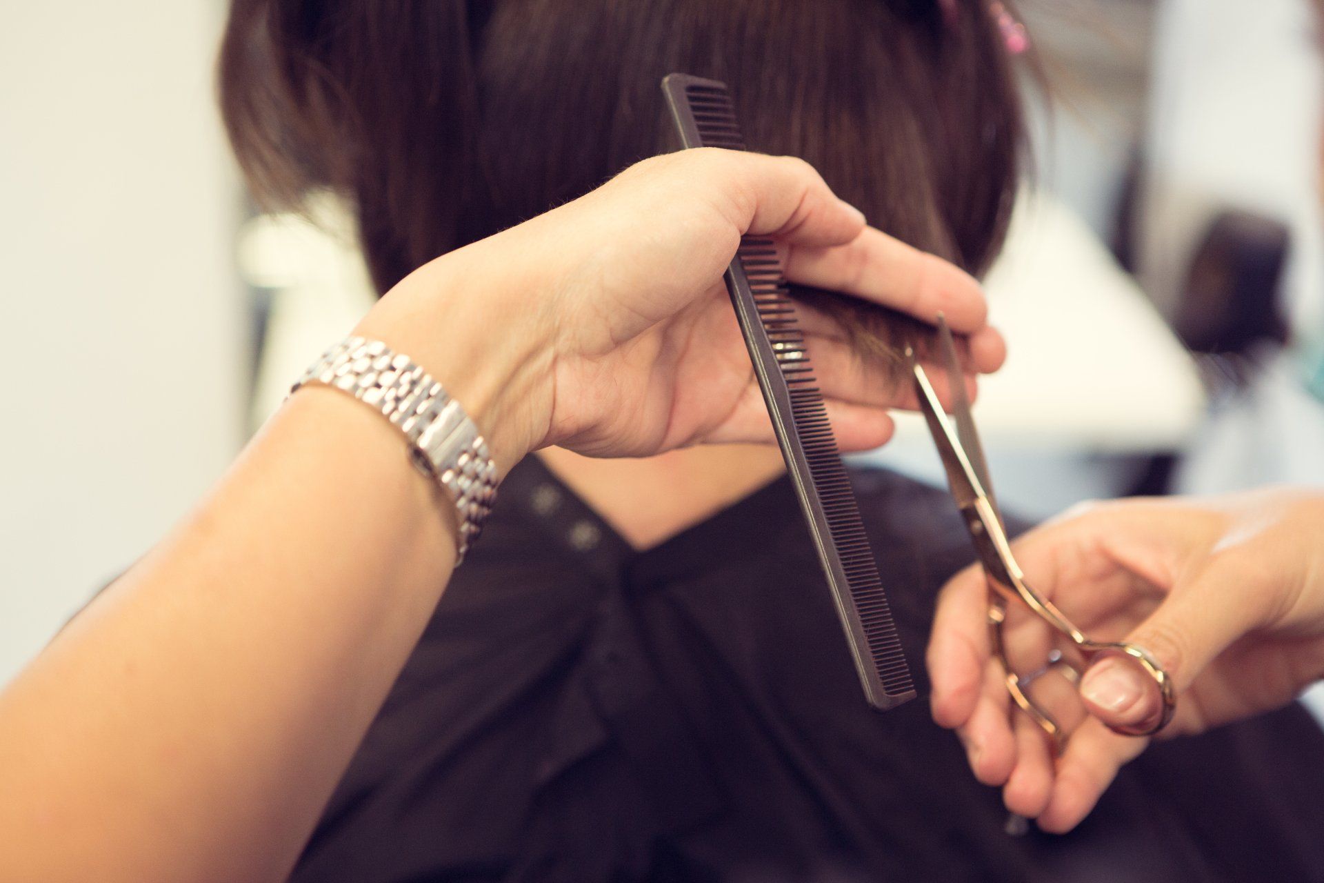 Eine Frau lässt sich von einem Friseur die Haare schneiden.