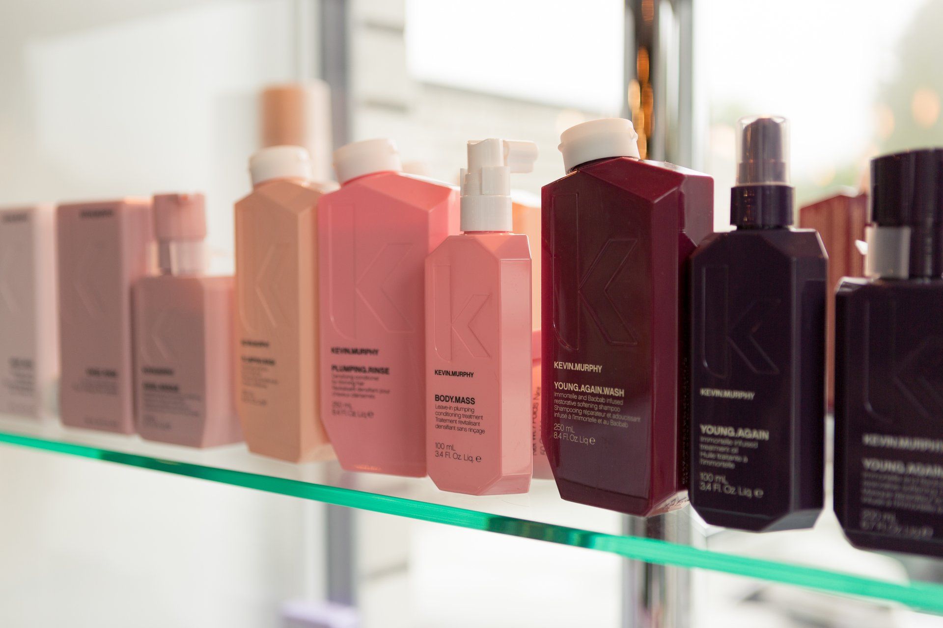 Auf einem Glasregal stehen mehrere Flaschen mit Haarpflegeprodukten.