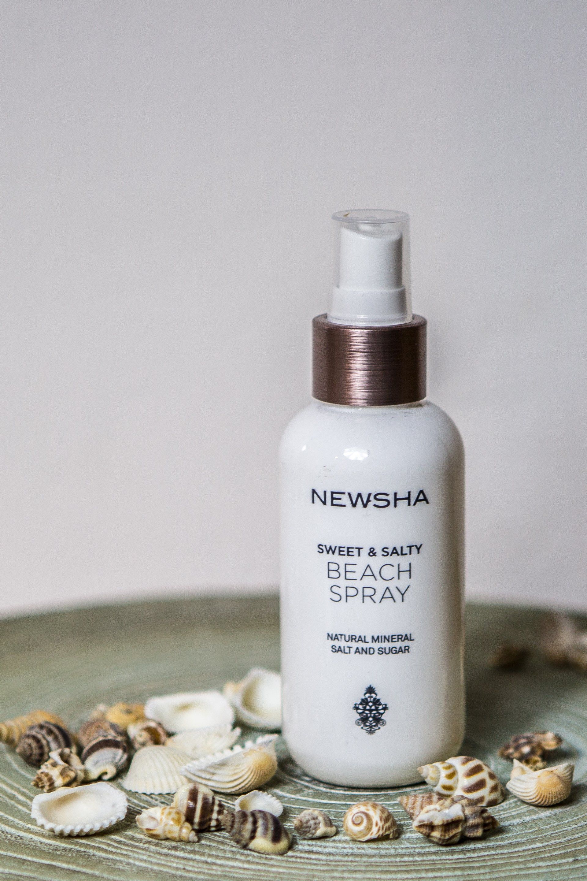 Eine Flasche Pfirsichspray steht auf einem Tisch, umgeben von Muscheln.