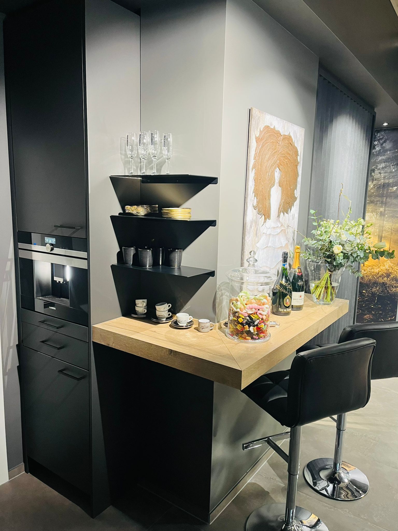 Eine Küche mit Bar, Hockern, Regalen und einem Gemälde an der Wand.