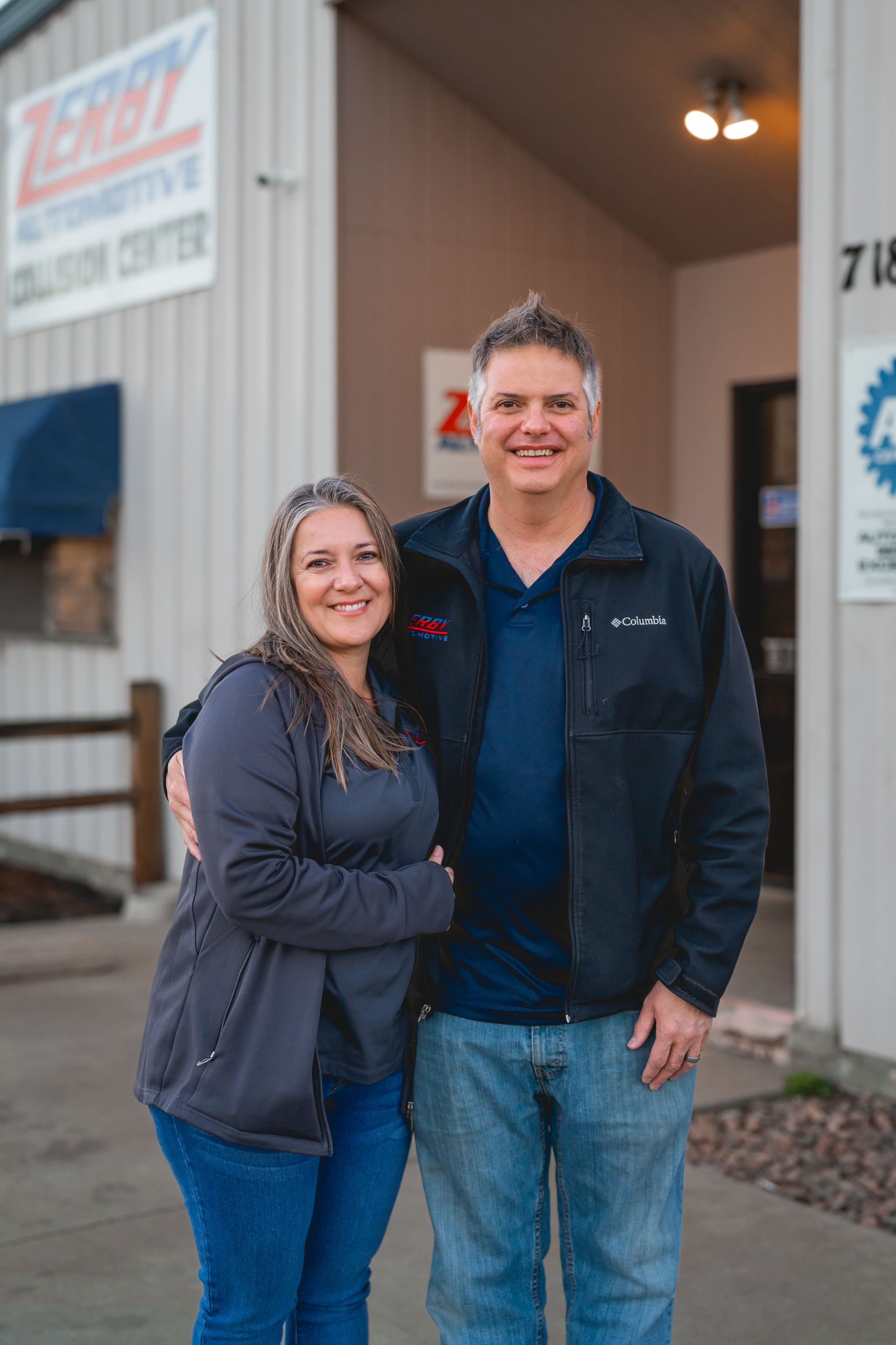 A man and a woman are posing for a picture in front of a building.
