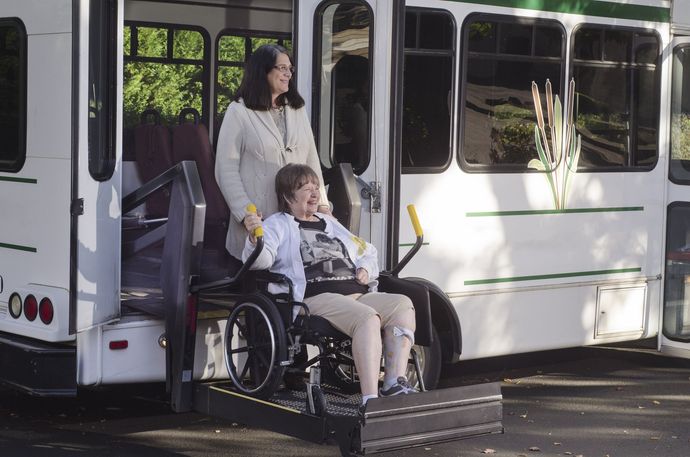 woman in a wheelchair is helped off a van using a chair lift