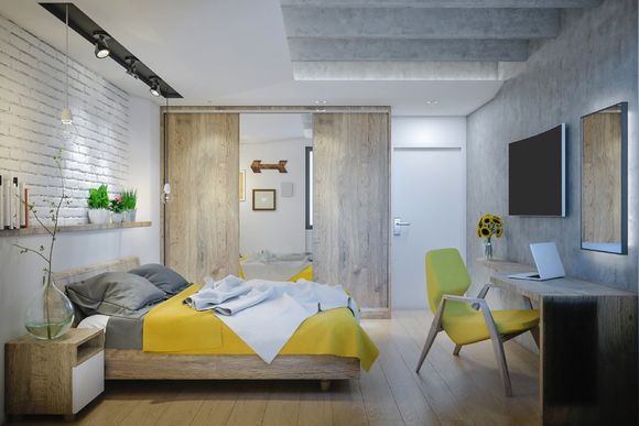 camera da letto con muretto in mattoncini e sedia gialla