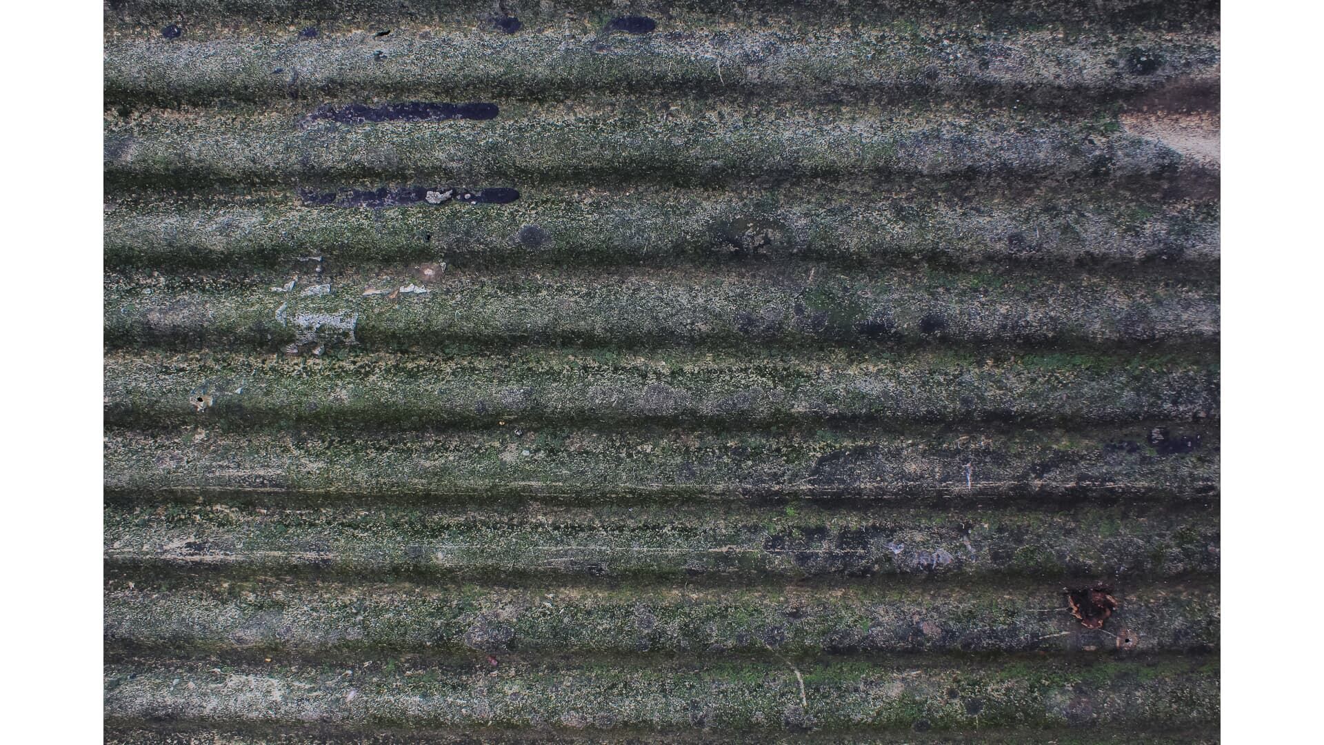 Corrugated metal surface with green and gray hues, weathered with horizontal ridges.