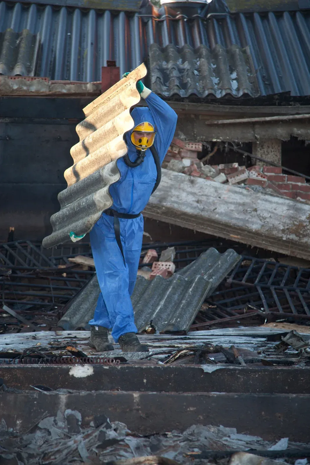 A man wearing a hard hat and goggles is standing in a room.