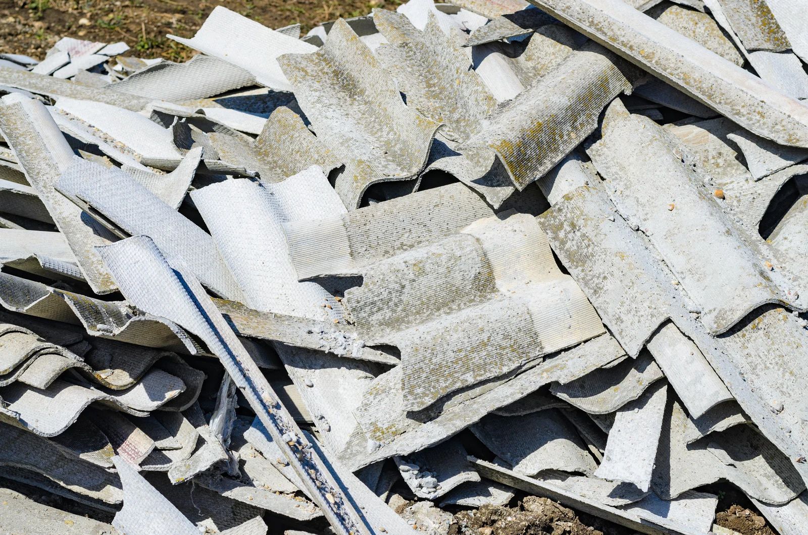 Pile of broken white and gray roofing shingles stacked outdoors