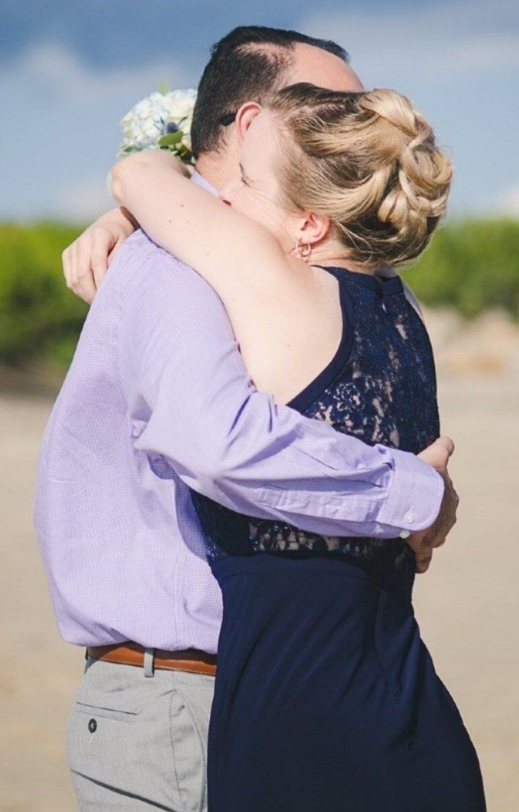 A woman in a blue dress is hugging a man in a purple shirt