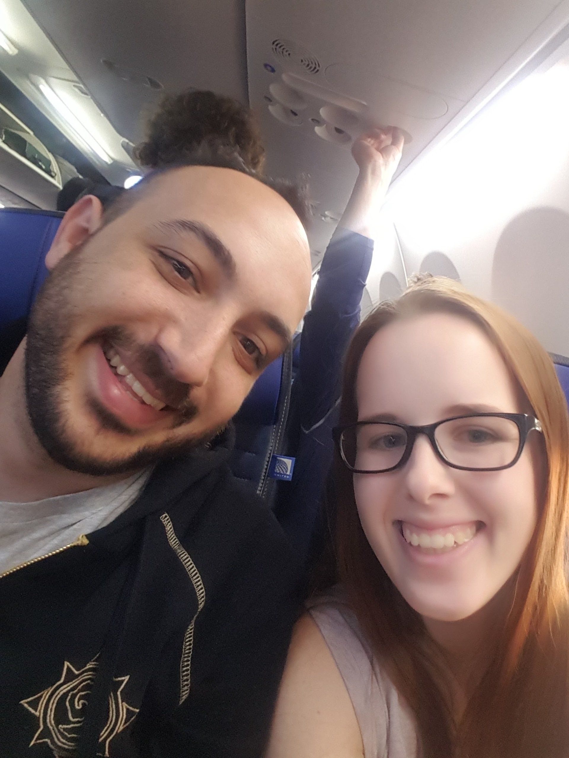 A man and a woman are posing for a picture on an airplane