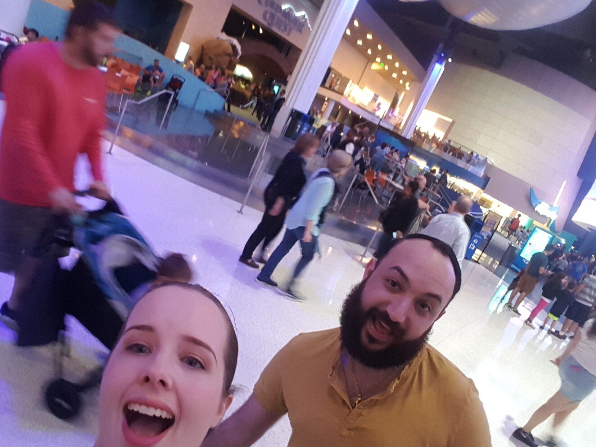 A man and a woman are taking a selfie in a mall.