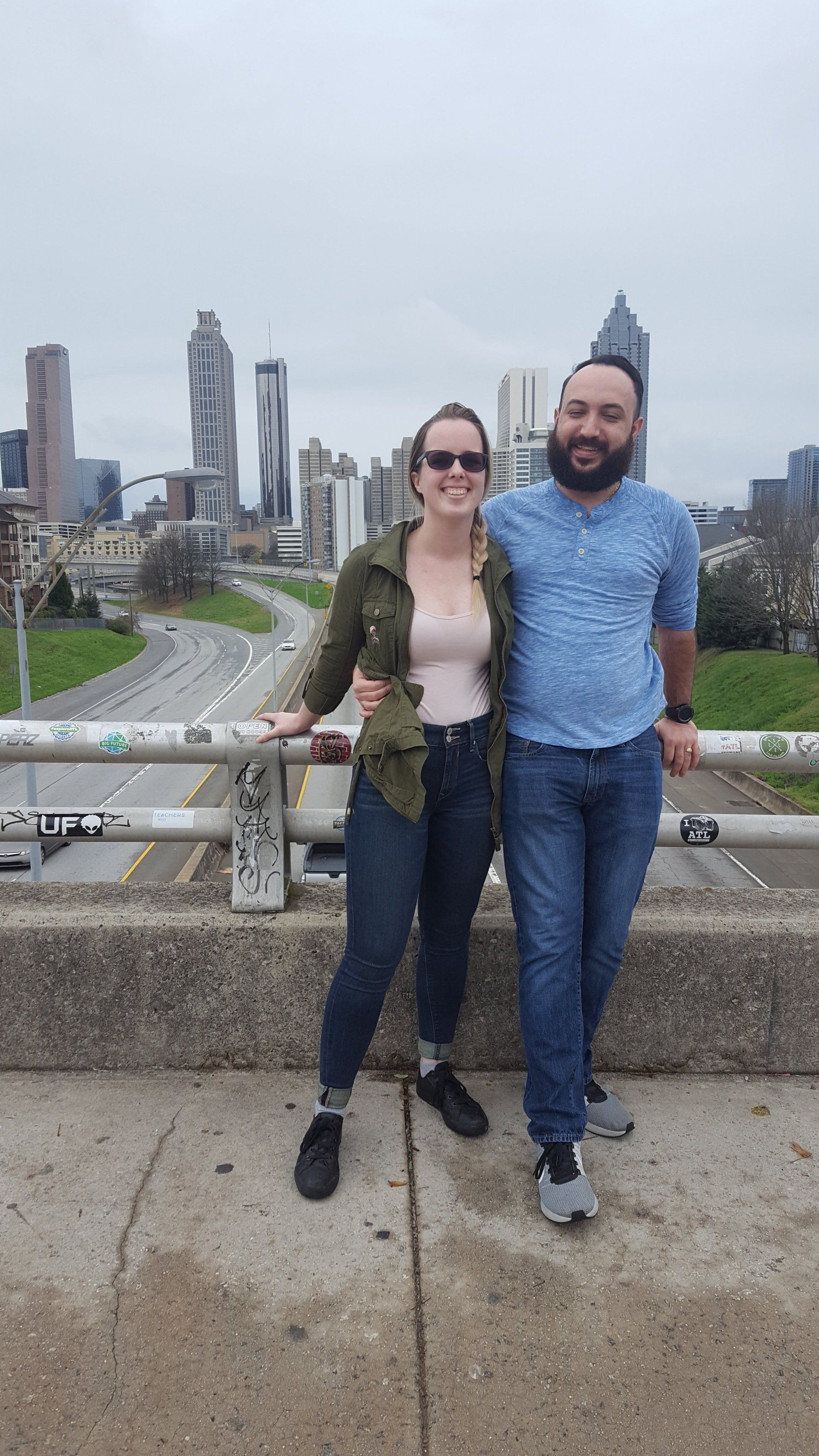 A man and a woman are posing for a picture on a bridge.
