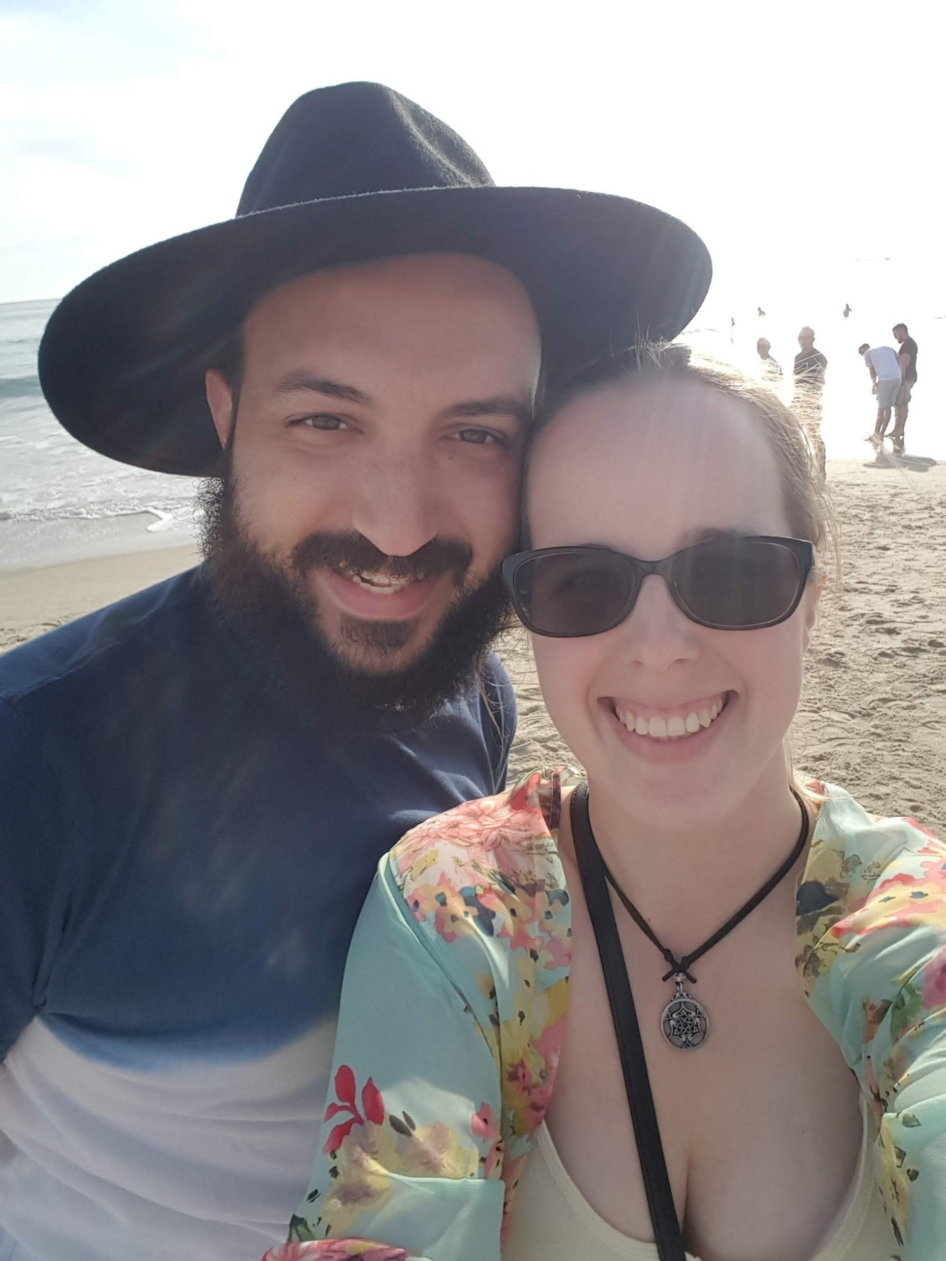 A man and a woman are posing for a picture on the beach