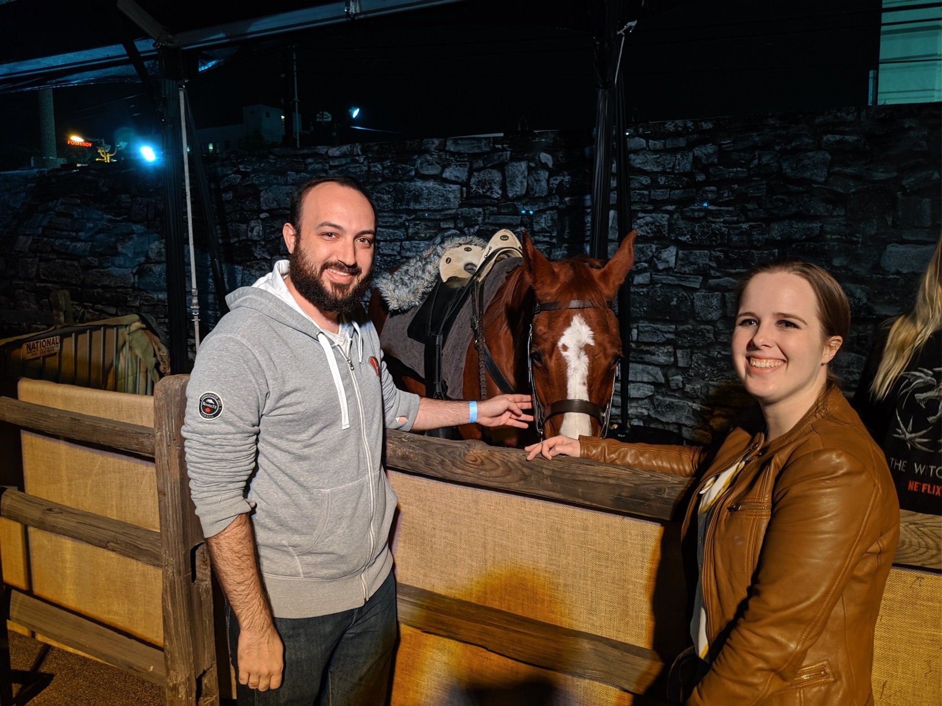 A man and a woman are standing next to a horse in a stable.