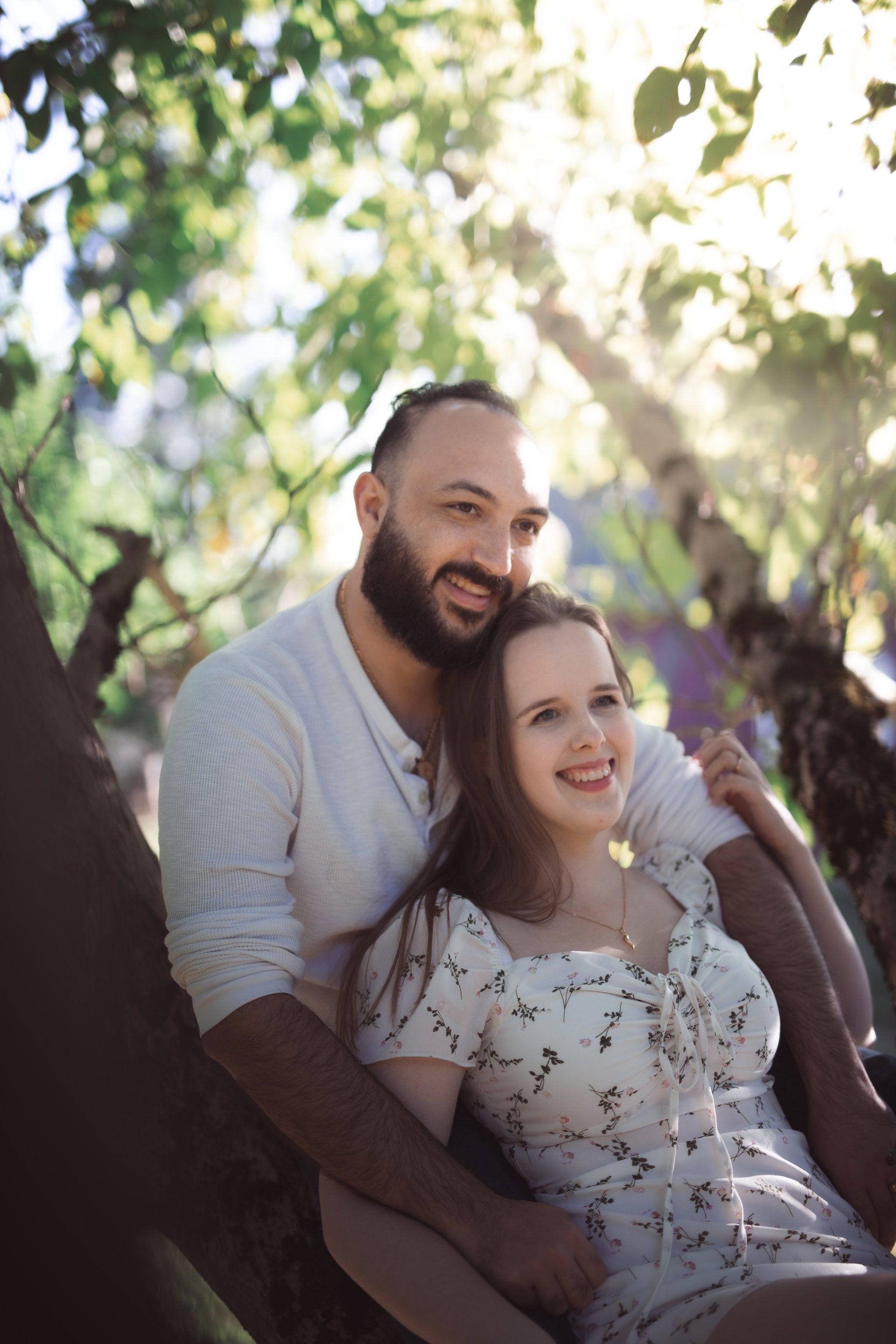 A man and a woman are sitting on a tree branch.