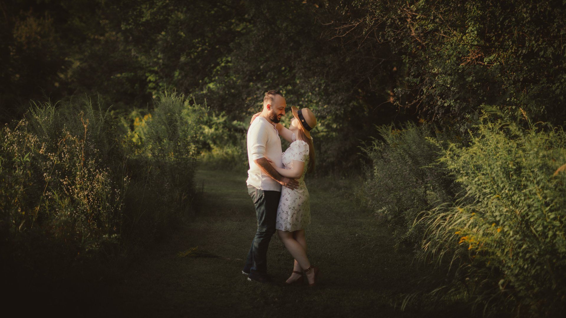 A man and a woman are kissing in the woods.