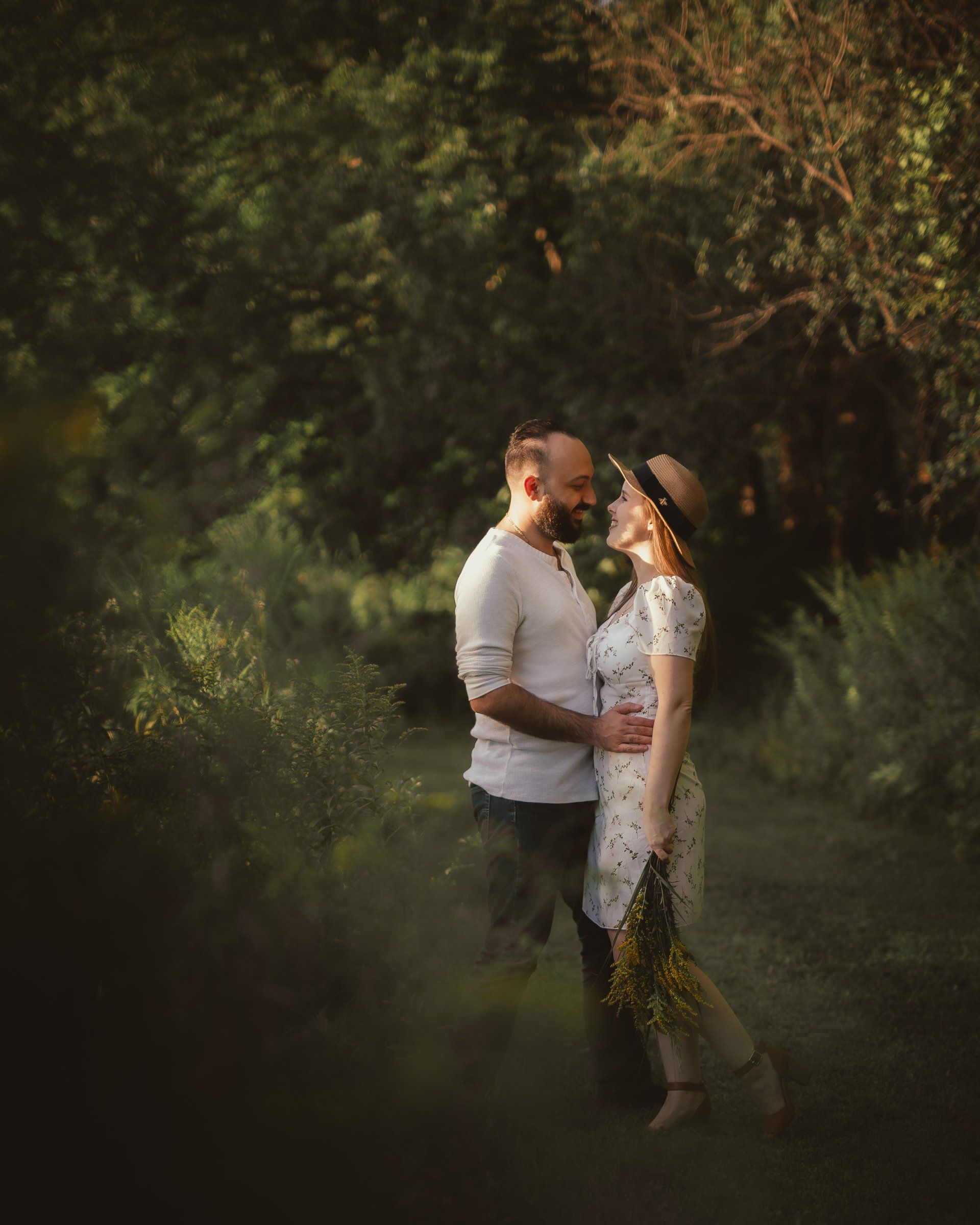 A man and a woman are standing next to each other in the woods.