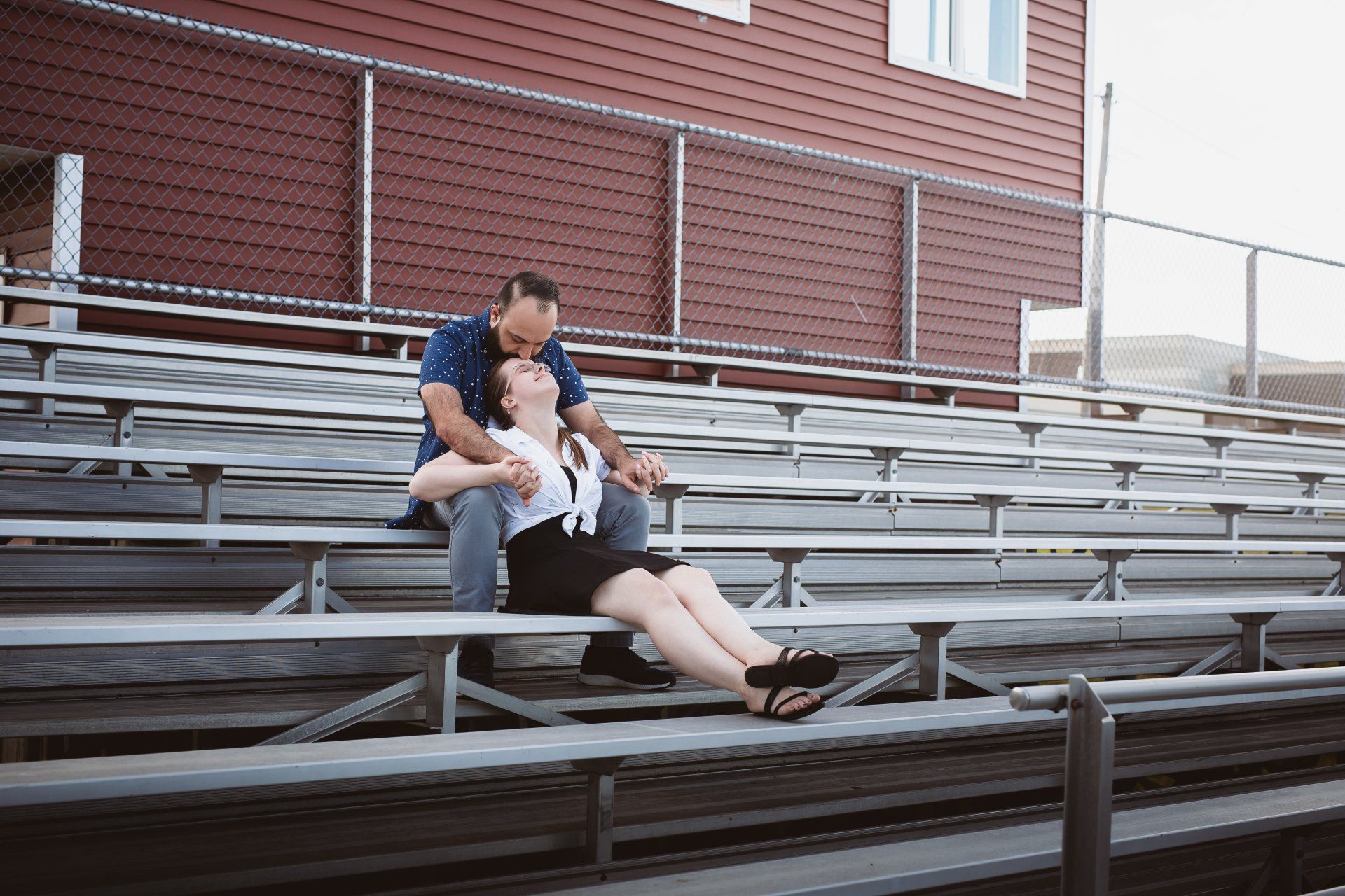 A man and a woman are sitting on the bleachers of a stadium.