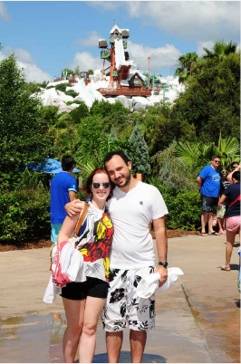 A man and a woman are posing for a picture in front of a water park.