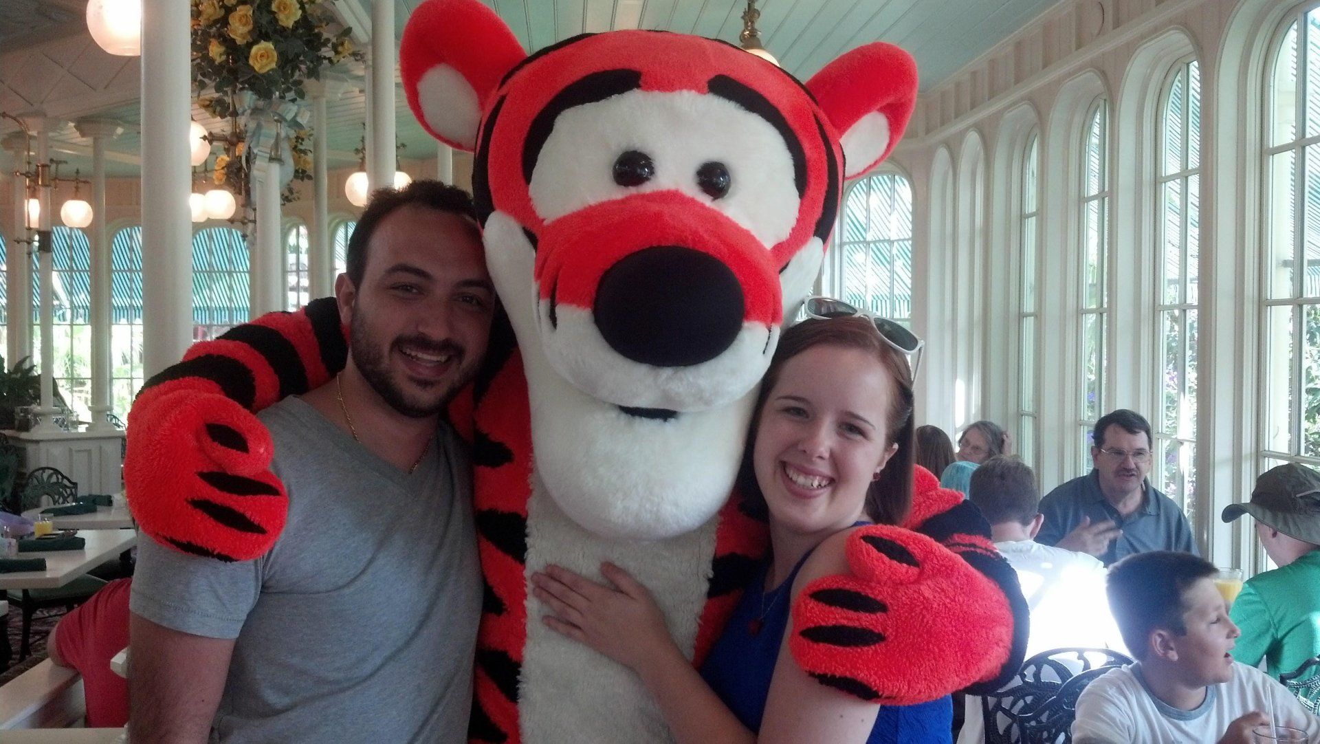 A man and a woman are posing for a picture with a tigger mascot.