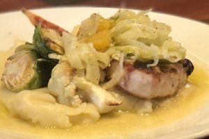 A close up of a plate of food with meat and vegetables on a table.