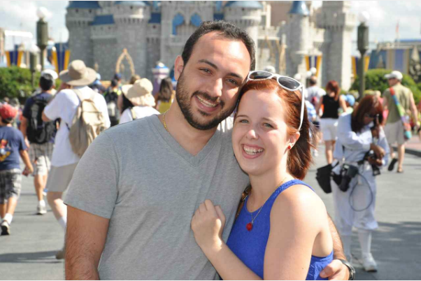 A man and a woman are posing for a picture in front of a castle