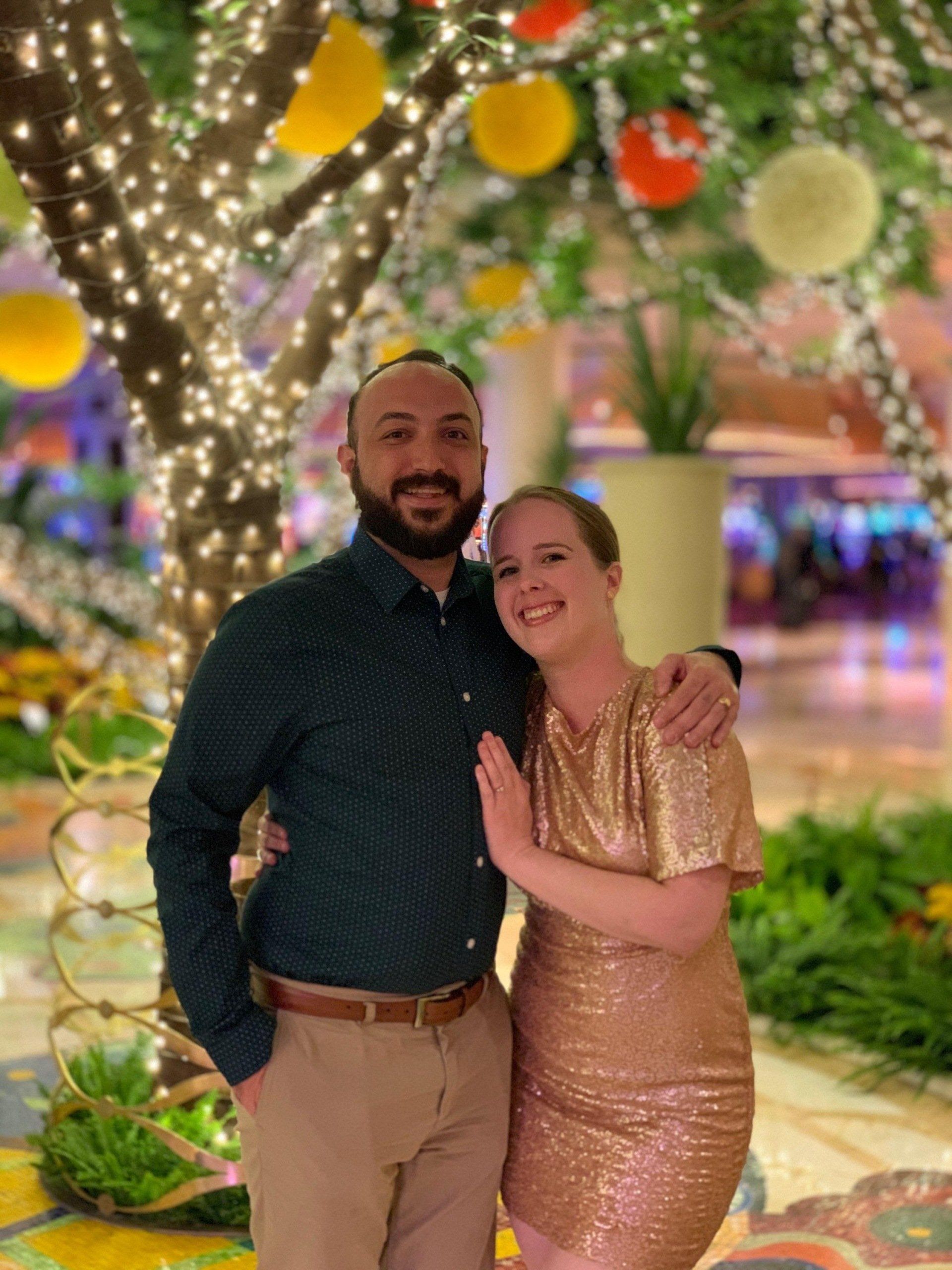A man and a woman are posing for a picture in front of a tree.