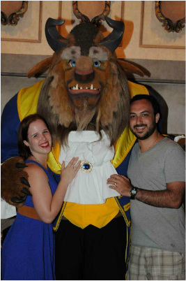 A man and a woman pose for a picture with the beast from beauty and the beast