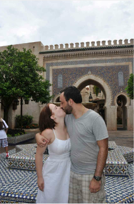 A man and woman kissing in front of a building