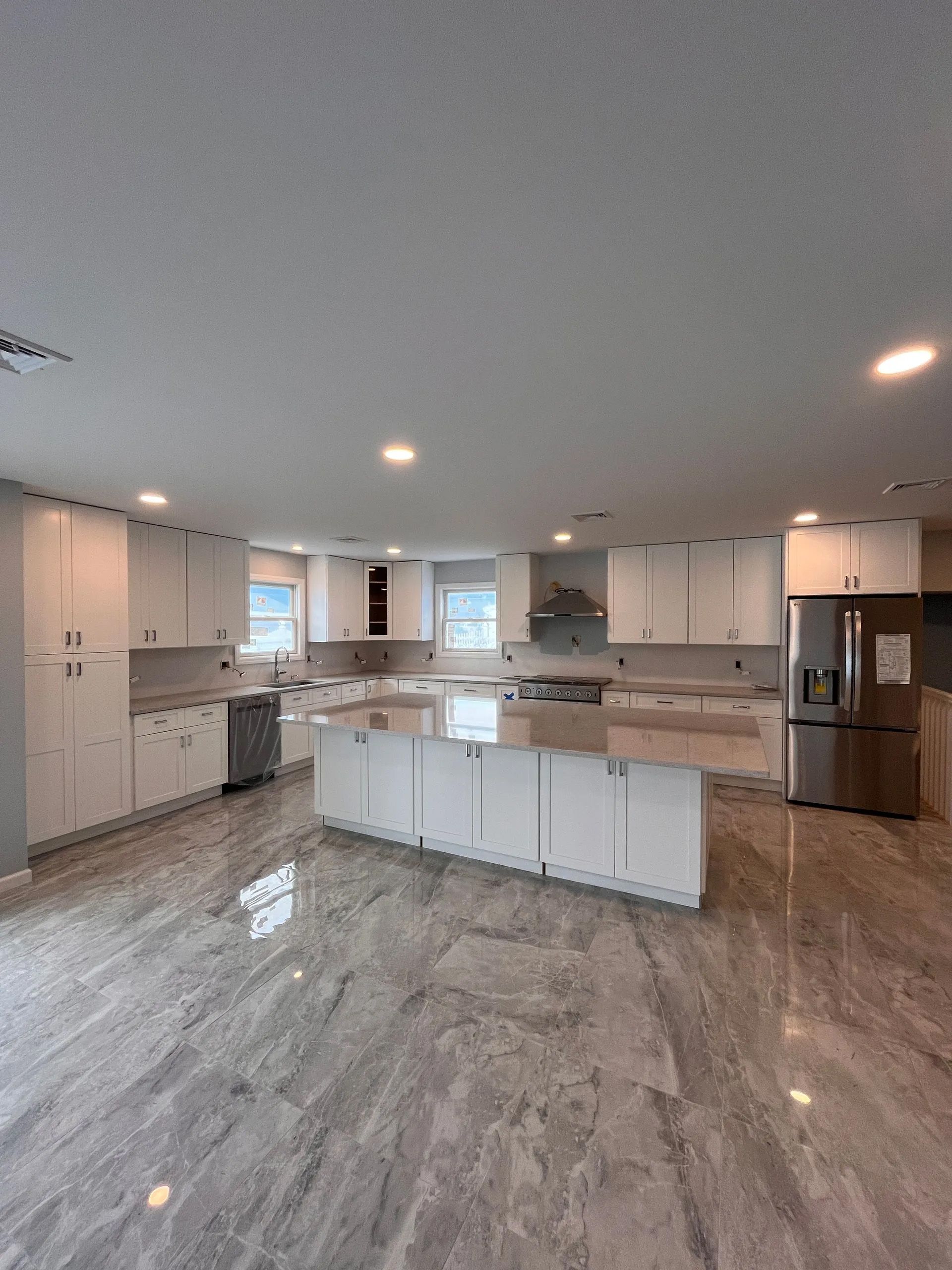 A large kitchen with white cabinets and a marble floor