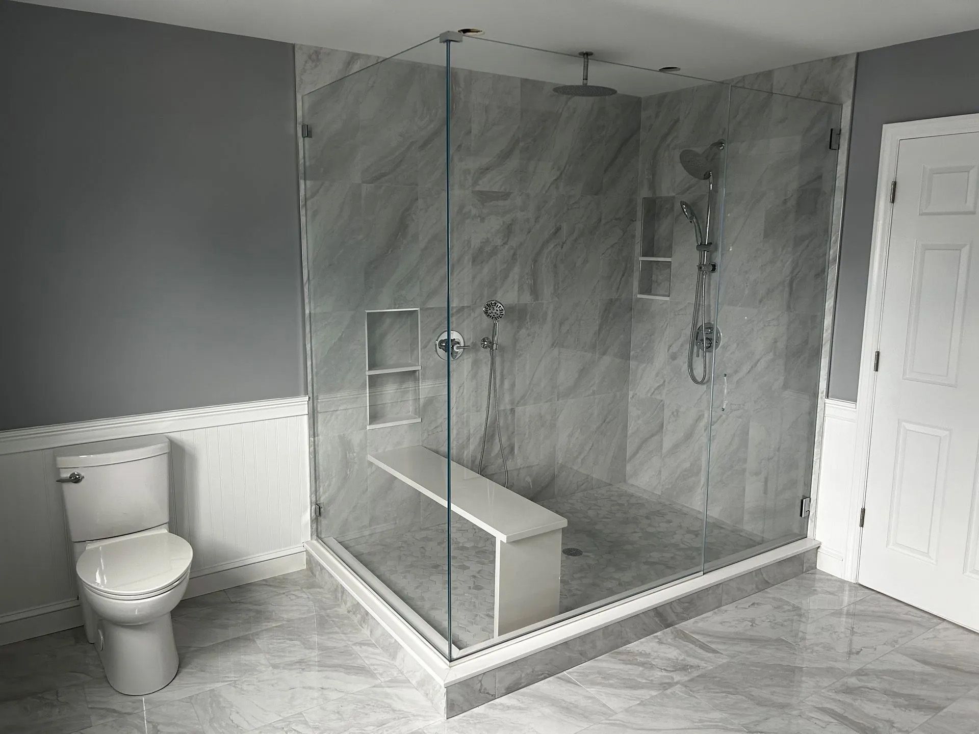 A bathroom with a toilet and a walk in shower with a glass door.