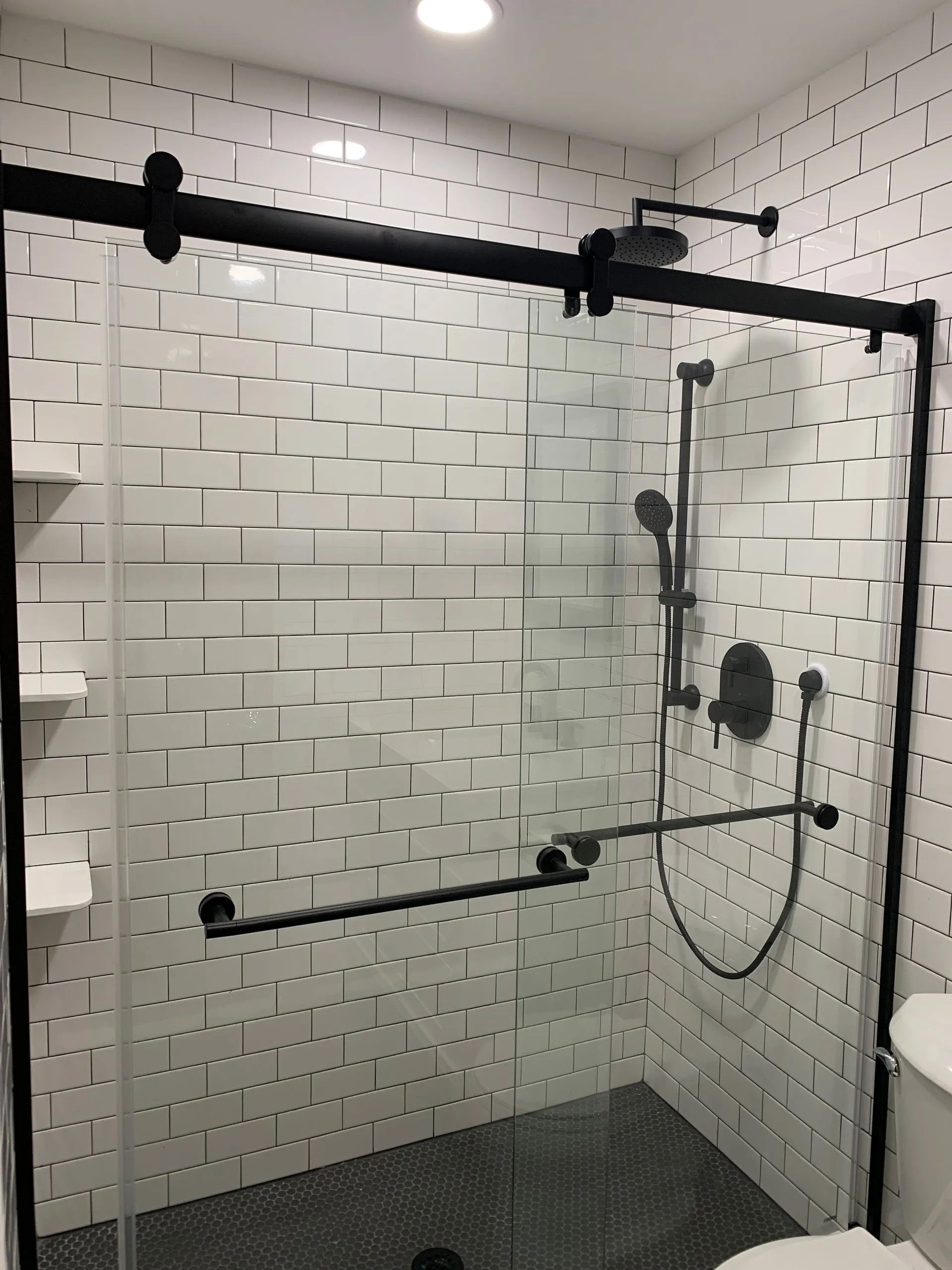 A bathroom with white tiles and a sliding glass shower door