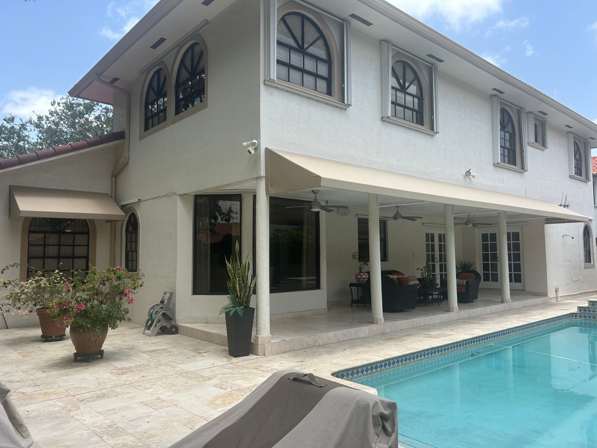 A car is parked under a canopy in front of a house