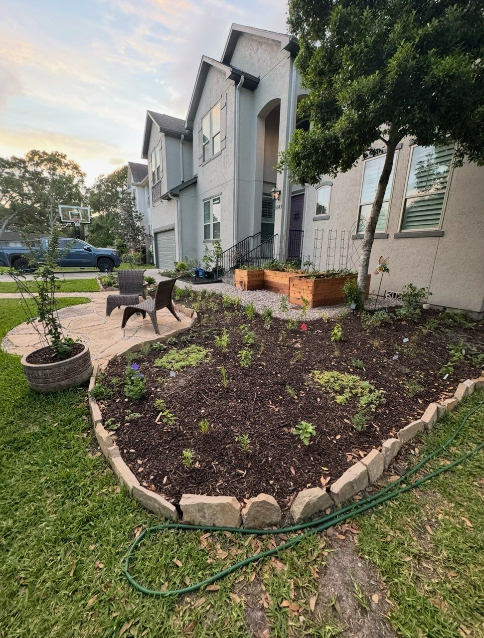A landscaped front yard with a house in the background. Flowerbeds, seating area, and a tree are featured.