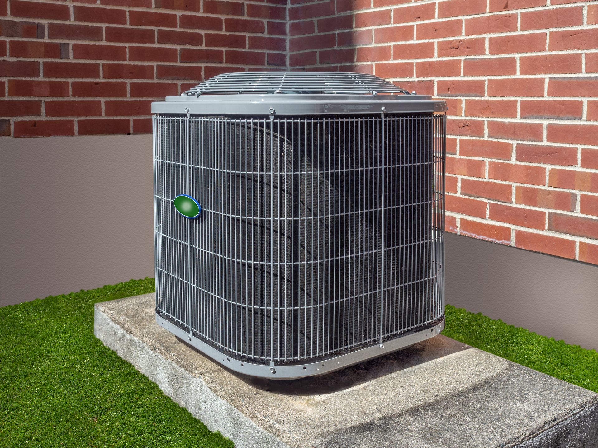 An air conditioner is sitting on top of a concrete platform in front of a brick building.