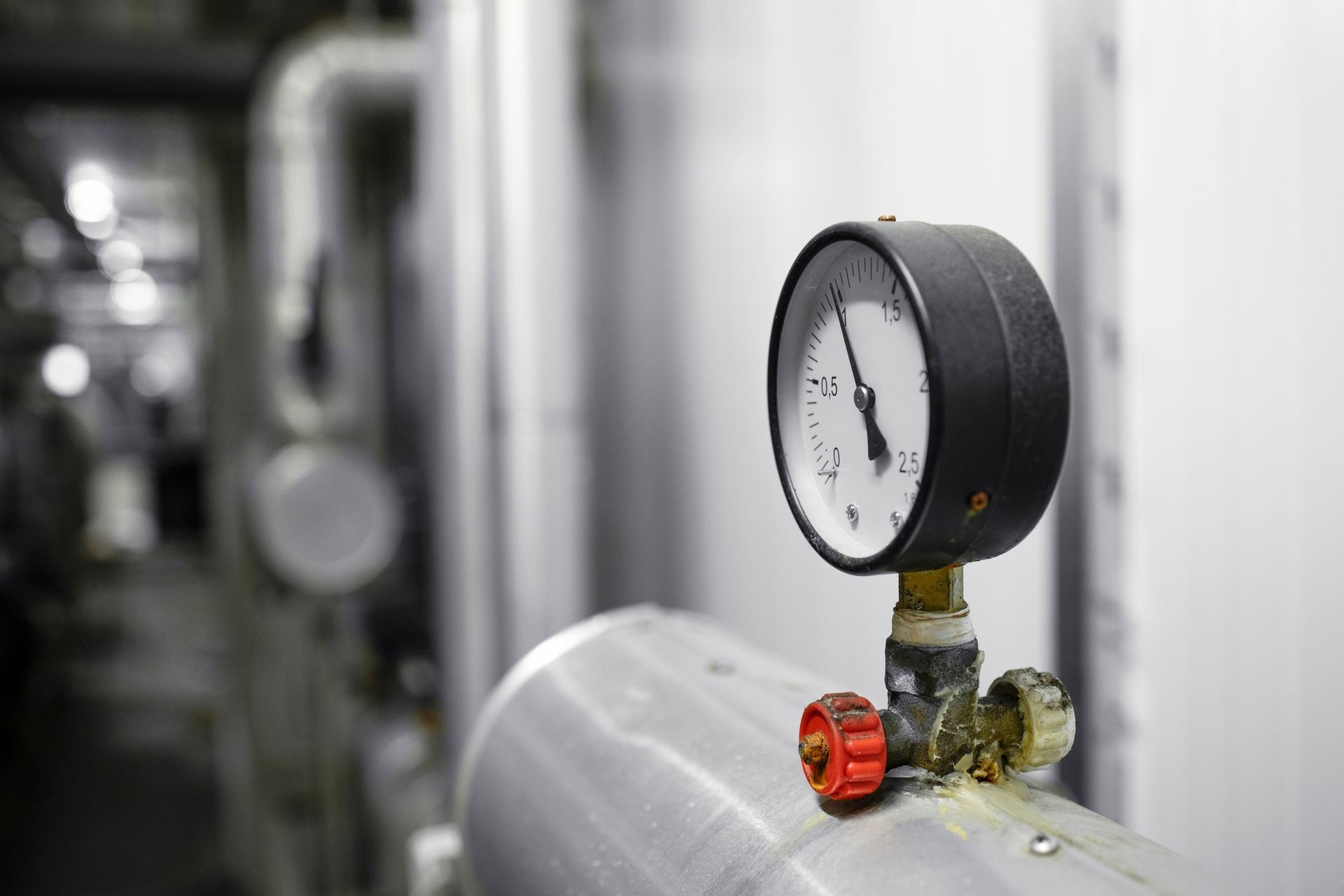 A close up of a pressure gauge on a pipe in a factory.