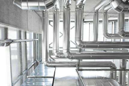 A bunch of metal pipes are hanging from the ceiling of a building.