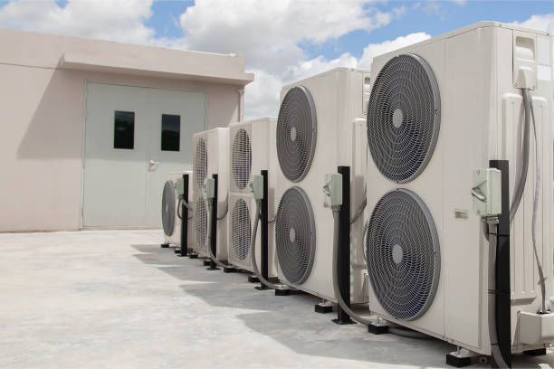 A row of air conditioners are lined up in front of a building.