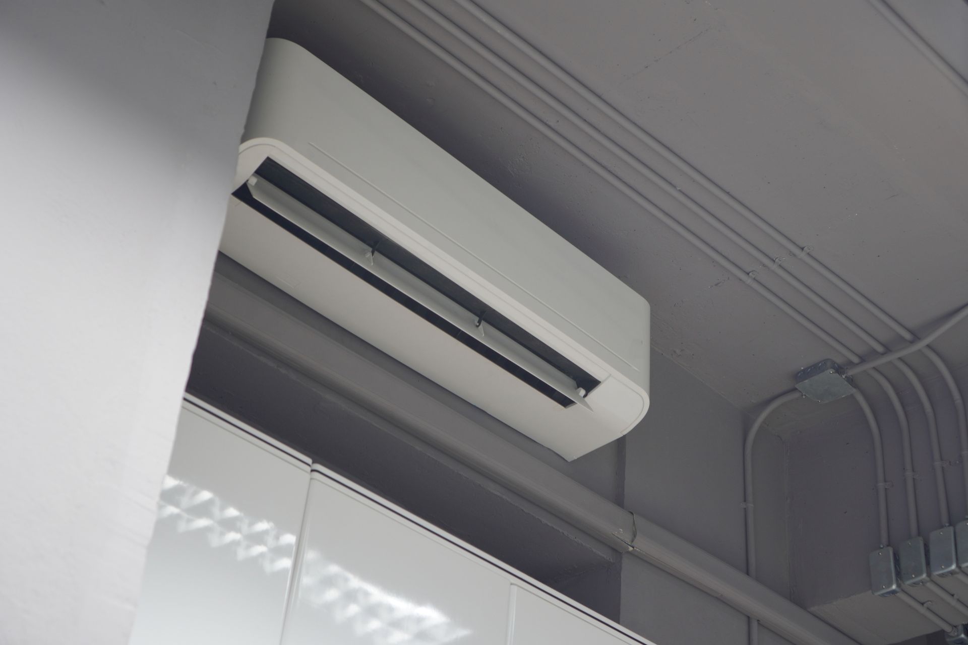 A white air conditioner is hanging from the ceiling of a room.