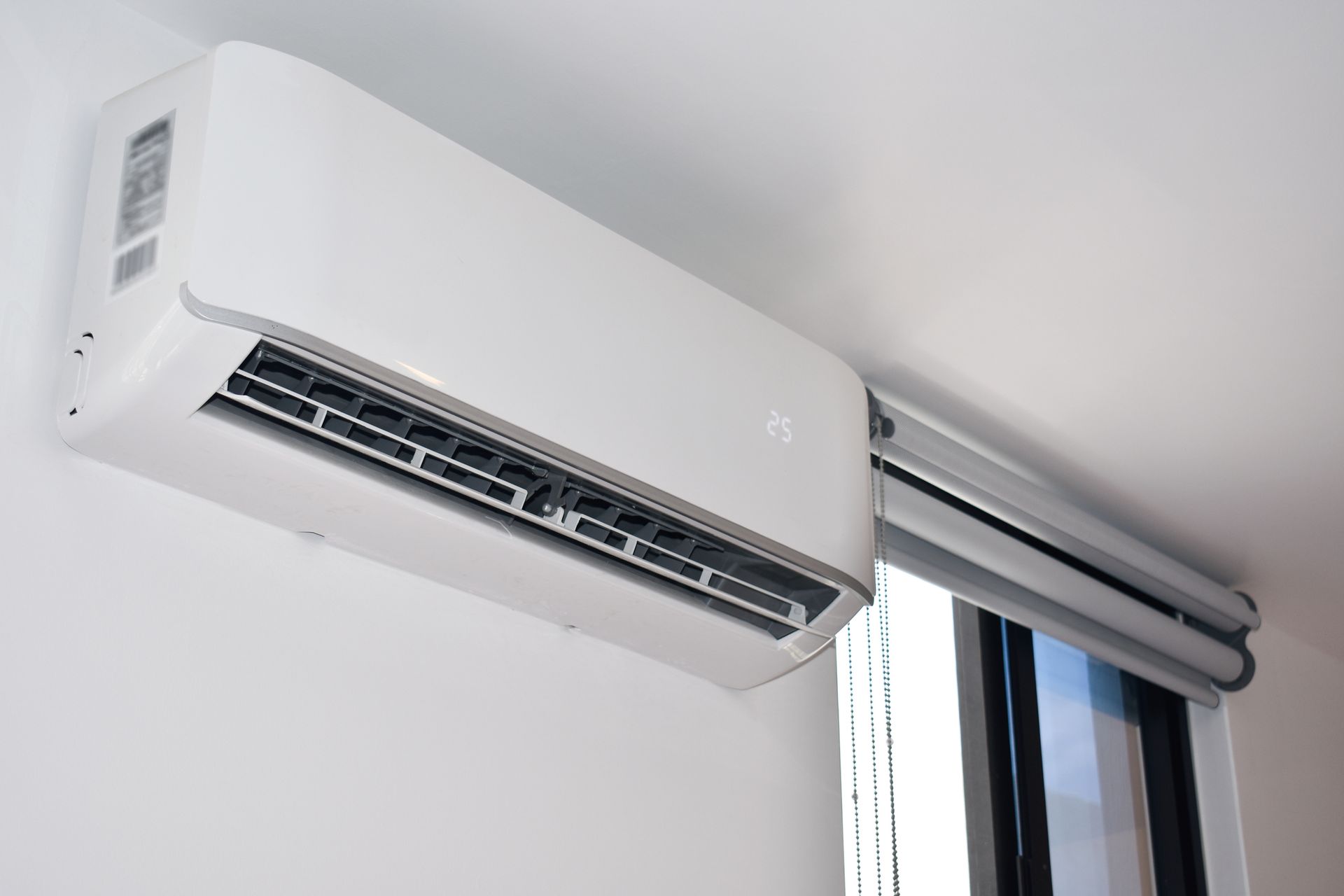 A white air conditioner is hanging from the ceiling next to a window.