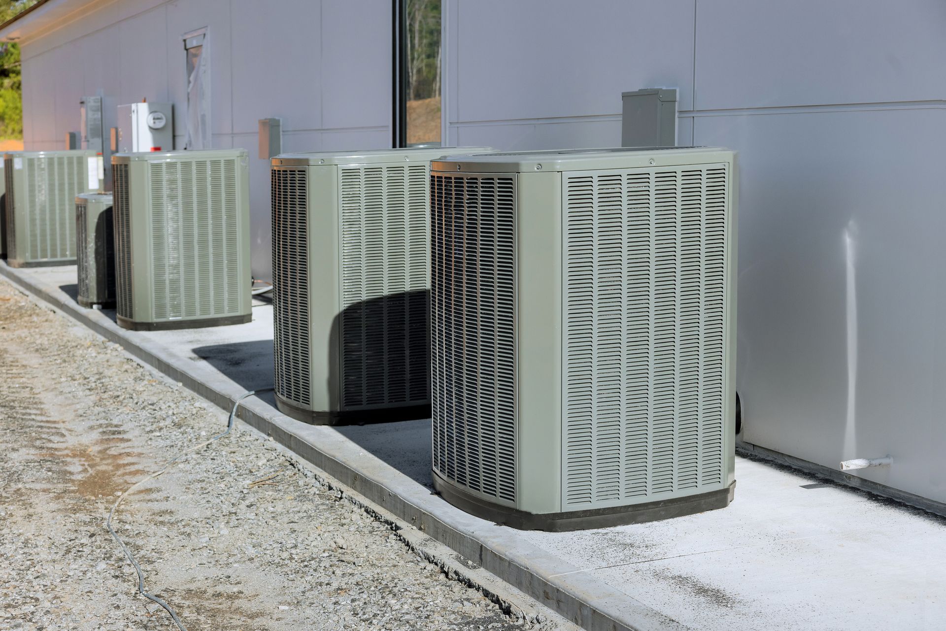 A row of air conditioners are sitting on the side of a building.