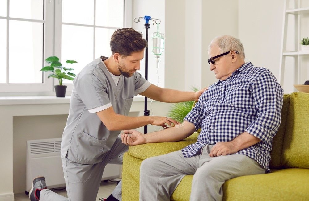 Doctor kneeling down to assist an elderly patient.