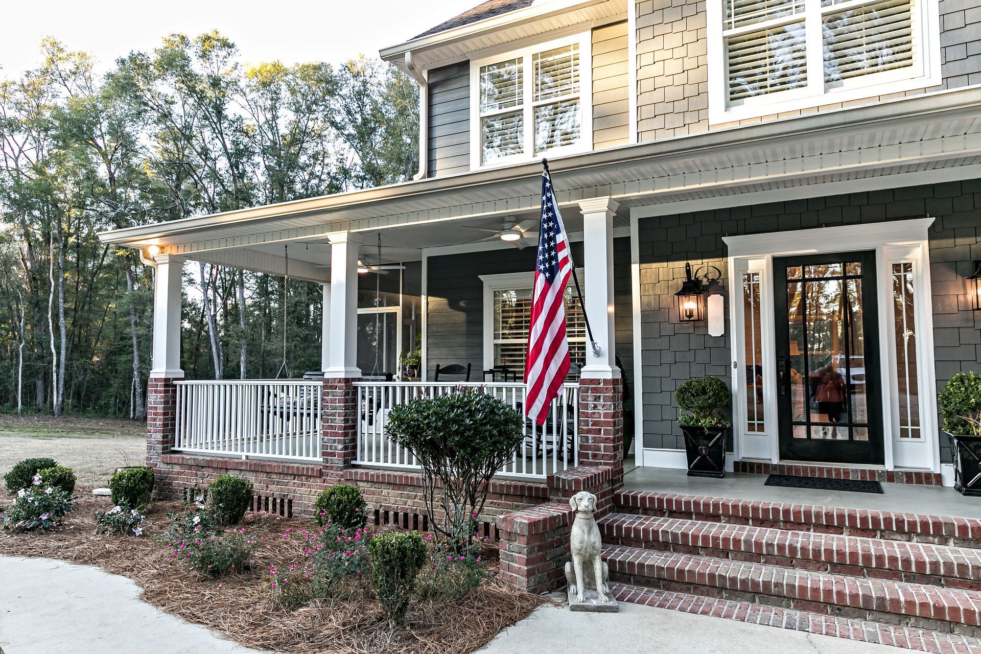 A large house with a large porch and an american flag on it.