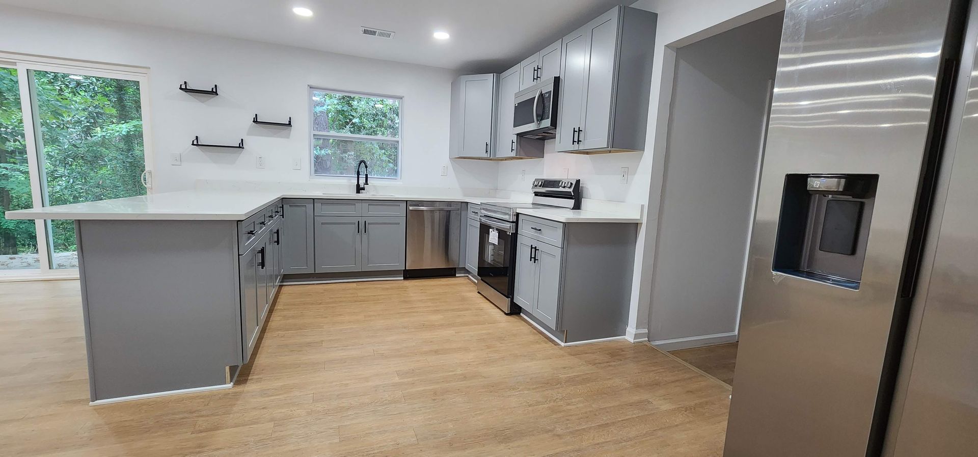 A kitchen with stainless steel appliances and gray cabinets.