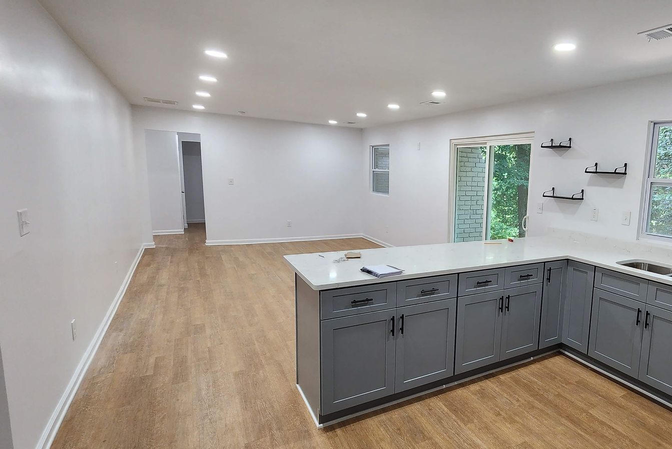 An empty kitchen with gray cabinets and a large island.