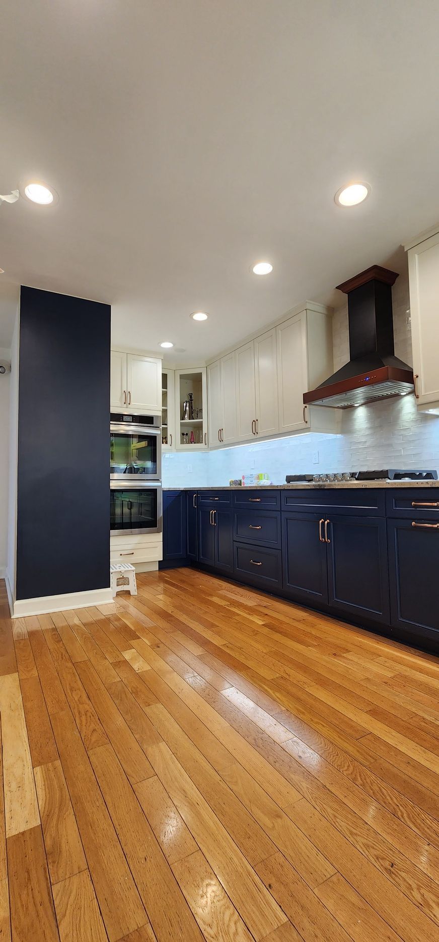 A kitchen with white cabinets , a stove , a sink , and a potted plant.