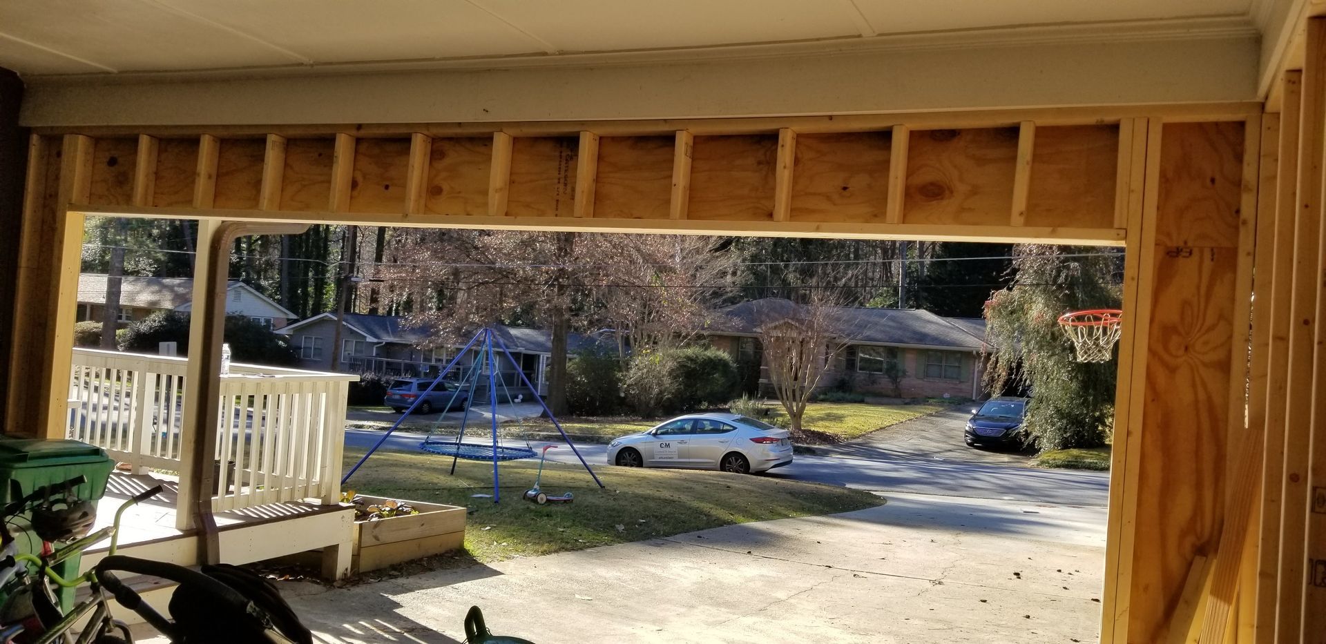 A car is parked in the driveway of a house under construction.