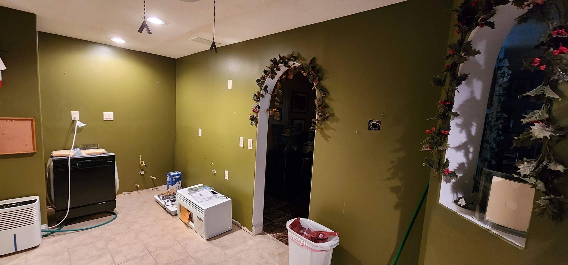 A room with green walls and a white trash can in it.