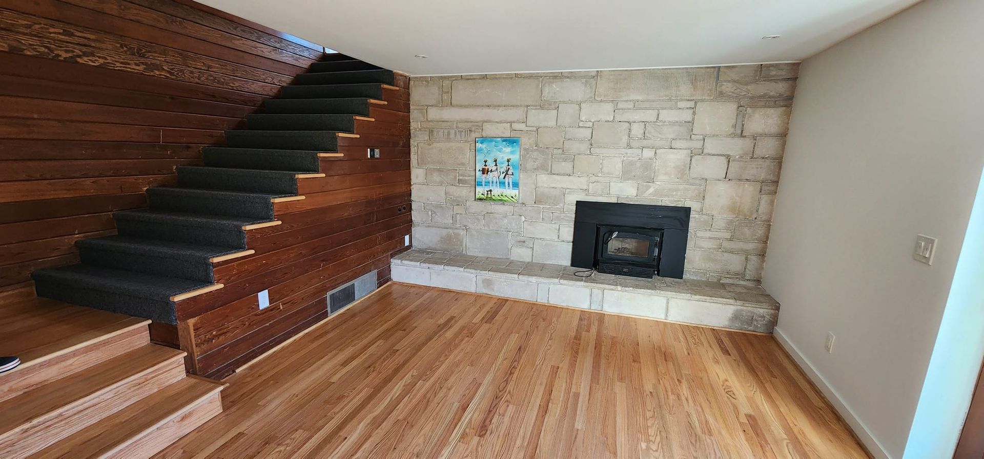 A living room with hardwood floors , stairs and a fireplace.