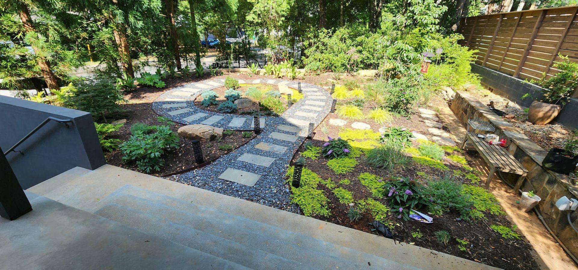 A staircase leading up to a garden with lots of plants and trees.